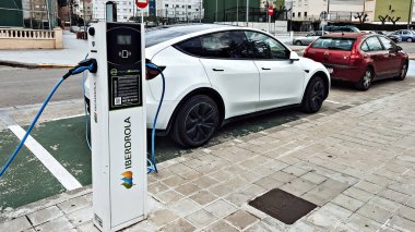 Valencia, İspanya - 23 Mayıs 2025: Elektrikli araç şarj istasyonu Tesla Y modelini park etmiş, çevre dostu taşımacılık ve modern şehir planlamasını ön plana çıkarmıştır.