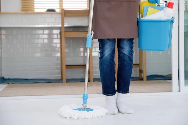 Mulher, limpeza de rotina diária no chão da casa com vassoura e