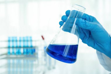 Tıbbi ya da bilimsel araştırmacı ya da insan doktoru laboratuarda bir test tüpü dolusu temiz çözeltiye bakıyor.