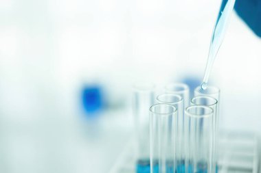 Tıbbi ya da bilimsel araştırmacı ya da insan doktoru laboratuarda bir test tüpü dolusu temiz çözeltiye bakıyor.