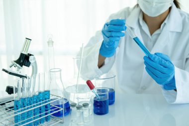 Tıbbi ya da bilimsel araştırmacı ya da insan doktoru laboratuarda bir test tüpü dolusu temiz çözeltiye bakıyor.
