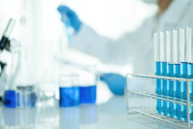 Tıbbi ya da bilimsel araştırmacı ya da insan doktoru laboratuarda bir test tüpü dolusu temiz çözeltiye bakıyor.