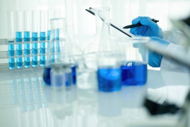 Tıbbi ya da bilimsel araştırmacı ya da insan doktoru laboratuarda bir test tüpü dolusu temiz çözeltiye bakıyor.