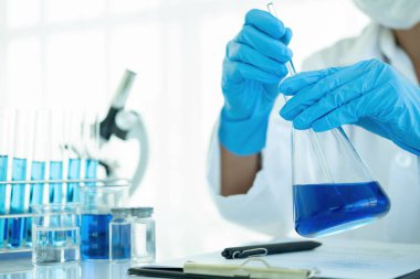 Tıbbi ya da bilimsel araştırmacı ya da insan doktoru laboratuarda bir test tüpü dolusu temiz çözeltiye bakıyor.