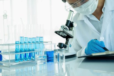 Tıbbi ya da bilimsel araştırmacı ya da insan doktoru laboratuarda bir test tüpü dolusu temiz çözeltiye bakıyor.