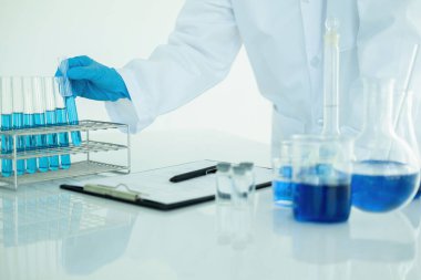 Tıbbi ya da bilimsel araştırmacı ya da insan doktoru laboratuarda bir test tüpü dolusu temiz çözeltiye bakıyor.
