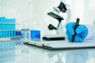 Tıbbi ya da bilimsel araştırmacı ya da insan doktoru laboratuarda bir test tüpü dolusu temiz çözeltiye bakıyor.