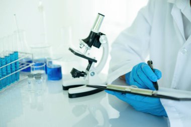 Tıbbi ya da bilimsel araştırmacı ya da insan doktoru laboratuarda bir test tüpü dolusu temiz çözeltiye bakıyor.