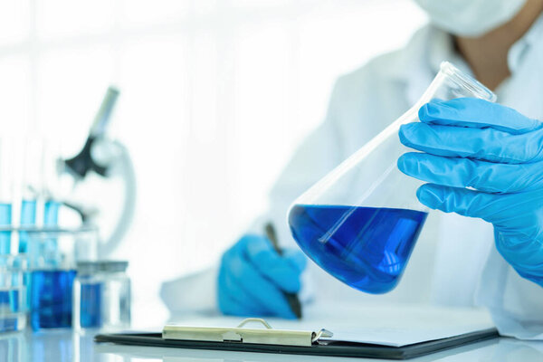 Medical or scientific researcher or man doctor looking at a test tube of clear solution in a laboratory