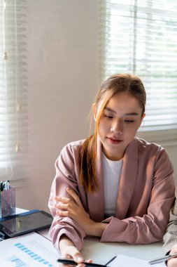 İş kadını iş yerinde ya da evde koltukta oturup dizüstü bilgisayar üzerinde çalışıyor ve şirket için iş planı ve stratejiler oluşturmak için çizelgeler ve grafikler üzerindeki verileri analiz ediyor ve kağıtlara yazıyor. İş konsepti.