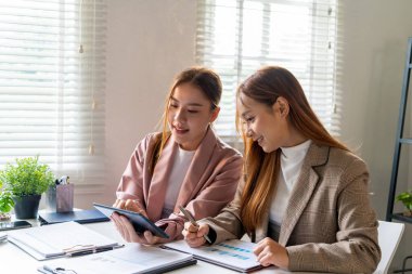 İş kadını iş yerinde ya da evde koltukta oturup dizüstü bilgisayar üzerinde çalışıyor ve şirket için iş planı ve stratejiler oluşturmak için çizelgeler ve grafikler üzerindeki verileri analiz ediyor ve kağıtlara yazıyor. İş konsepti.