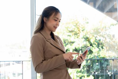 İş kadını iş yerindeki koltukta ya da evdeki koltukta oturuyor ve şirket için iş planı ve stratejiler oluşturmak için dizüstü bilgisayar üzerinde çalışıyor, grafikler ve kağıtlar üzerindeki verileri analiz ediyor ve kağıtlara yazıyor..