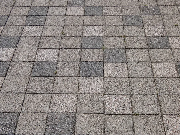 View of street pavement or a sidewalk made from small square bricks outdoors in a city