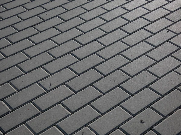 View of street pavement or a sidewalk made from small square bricks outdoors in a city