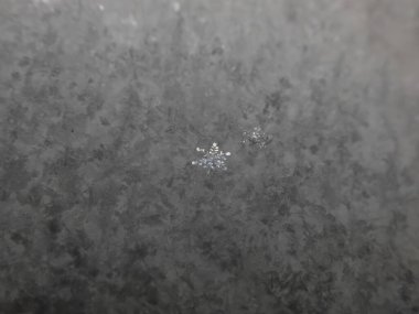 Tek bir parlak, güzel geometrik kar tanesinin makrosu ile desenli, koyu kar yüzeyi. Bir kar tanesinin detaylı görüntüsü