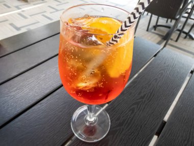 Prosecco, aperol, soda, portakal dilimleri ve buzlu Aperol kokteyli. Parlak güneş ışığıyla kaplı turuncu kokteyl camından güzel bir makro çekim.