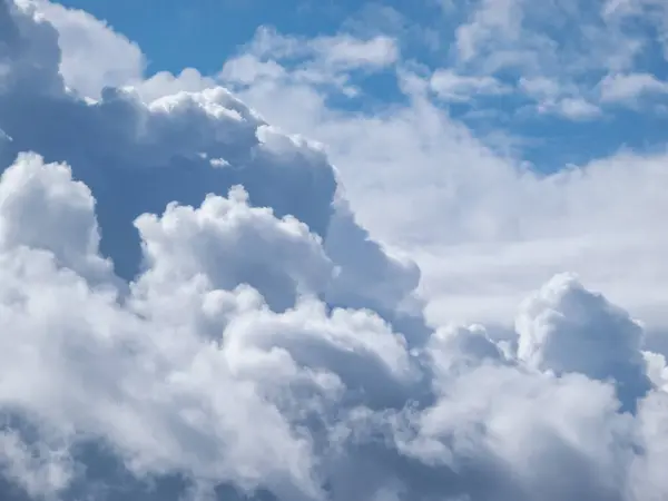 Güneşli bir günde kabarık beyaz bulutlu mavi gökyüzü manzarası. Karanlık gökyüzünün arka planı güzel beyaz bulutlarla aydınlandı.