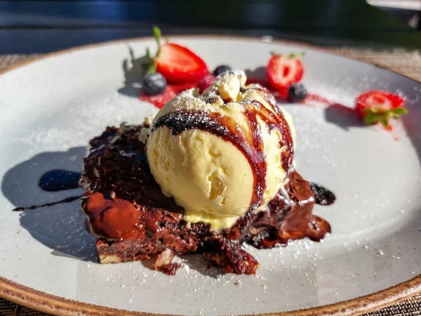 Close-up shot of a scoop of ice cream on a piece of brownie beautifully served on a dessert plate. Food presentation