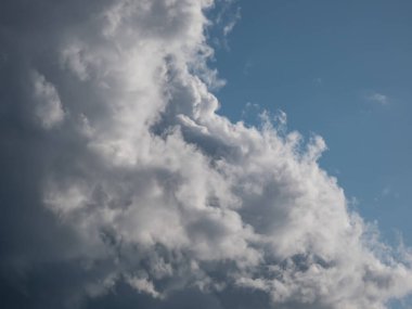 Güneşli bir günde pofuduk beyaz ve koyu bulutlu mavi gökyüzü manzarası. Karanlık gökyüzünün arka planı güzel beyaz bulutlar ve açık mavi gökyüzü ile aydınlandı.