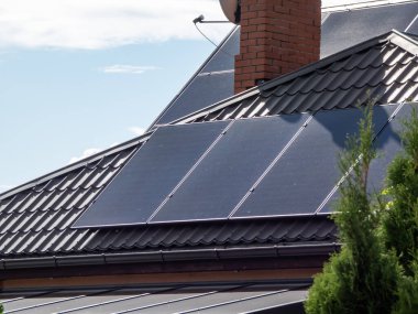 Çatıda parlak güneş ışığı altında fotovoltaik güneş panelleri monte edilmiş ve monte edilmiş bir çatı manzarası. Isınma ve elektrik için güneş pilleri olan çatı.