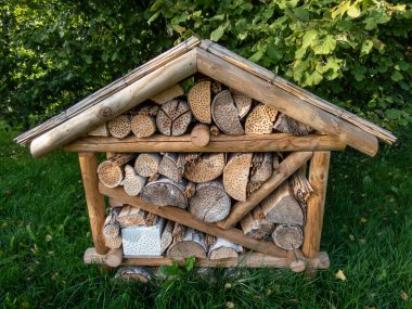 Böcek oteli ya da böcek evi - yeşil bitkilerin arasında böceklere barınak sağlamak için farklı bölümleri olan insan yapımı ahşap yapı