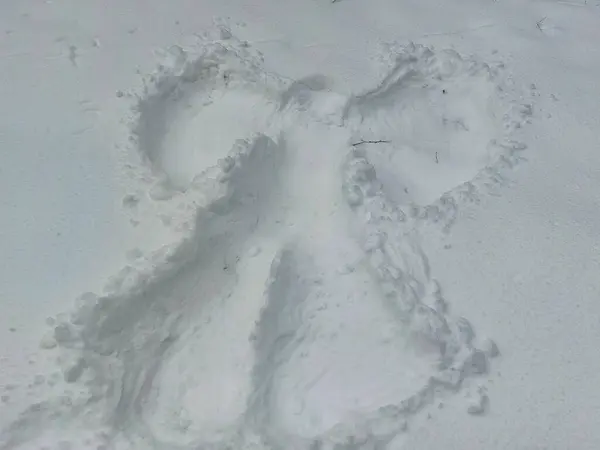Snow angel design made in fresh, deep snow, by lying on back and moving arms up and down, and legs from side to side in winter