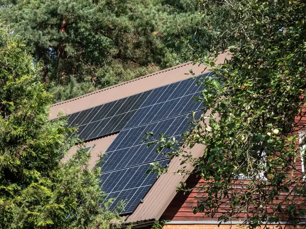 Çatıda parlak güneş ışığı altında fotovoltaik güneş panelleri monte edilmiş ve monte edilmiş bir çatı manzarası. Isınma ve elektrik için güneş pilleri olan çatı.