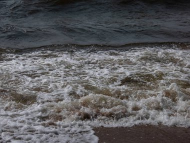 Baltık Denizi 'nin rüzgarlı gününde, üzerinde mavi gökyüzü olan büyük köpüklü dalgaların yakın çekimi. Güneşli bir günde Baltık Denizi 'ni resmeden deniz manzarası