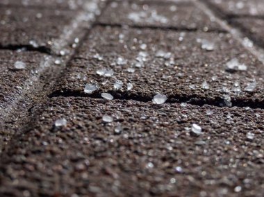 Kışın, buzlu kaldırım yüzeyindeki beyaz tuz tanelerini yakından çek. Yolları açık tutmak ve insanları kışın buzdan ve kardan korumak için tuz ekliyoruz..