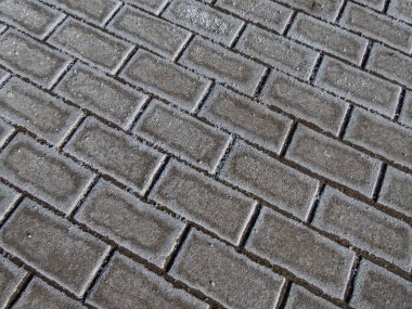 Kuru ve soğuk bir kışta, buz gibi kaldırımda beyaz tuz taneleriyle aşırı tuzlu yol yüzeyi.