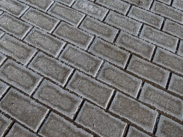 Kuru ve soğuk bir kışta, buz gibi kaldırımda beyaz tuz taneleriyle aşırı tuzlu yol yüzeyi.