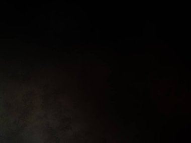 Siyah bir arka planın önünde duran takım elbiseli ve kravatlı bir adam.