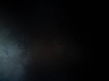 Takım elbiseli ve kravatlı bir adam karanlık bir arka planın önünde duruyor.