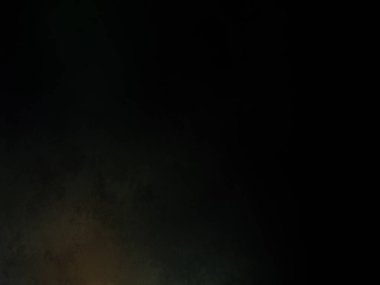 Siyah bir arka planın önünde duran takım elbiseli ve kravatlı bir adam.