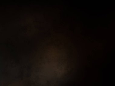 Siyah bir arka planın önünde duran takım elbiseli ve kravatlı bir adam.