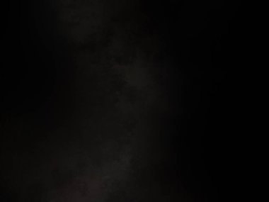 Siyah bir arka planın önünde duran takım elbiseli ve kravatlı bir adam.