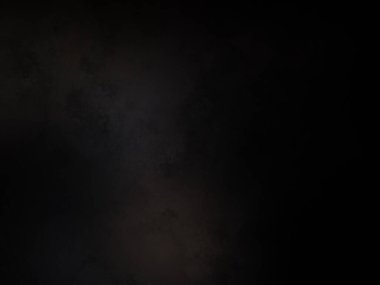 Siyah bir arka planın önünde duran takım elbiseli ve kravatlı bir adam.