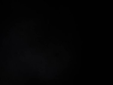 Siyah bir arka planın önünde duran takım elbiseli ve kravatlı bir adam.