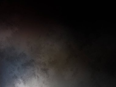 Takım elbiseli ve kravatlı bir adam karanlık bir arka planın önünde duruyor.