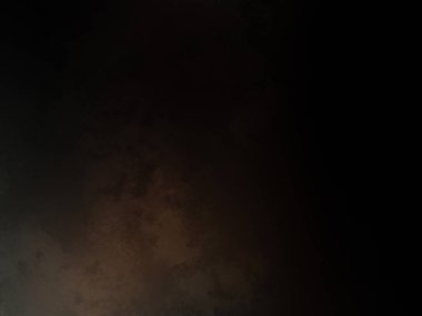 Takım elbiseli ve kravatlı bir adam karanlık bir arka planın önünde duruyor.