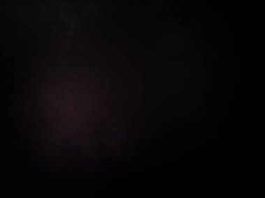 Siyah bir arka planın önünde duran takım elbiseli ve kravatlı bir adam.