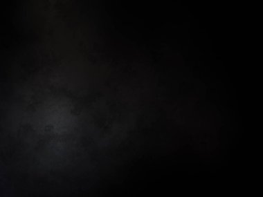 Siyah bir arka planın önünde duran takım elbiseli ve kravatlı bir adam.