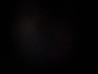 Siyah bir arka planın önünde duran takım elbiseli ve kravatlı bir adam.