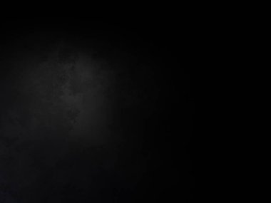 Takım elbiseli ve kravatlı bir adam karanlık bir arka planın önünde duruyor.