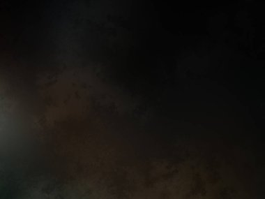 Karanlık bir yüzeyde kaykay süren bir adam.