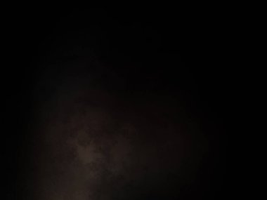 Takım elbiseli ve kravatlı bir adam karanlık bir arka planın önünde duruyor.