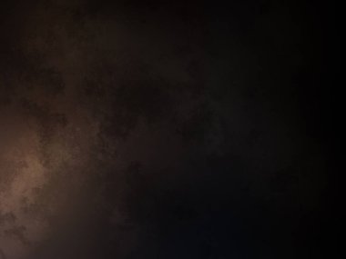 Takım elbiseli ve kravatlı bir adam karanlık bir arka planın önünde duruyor.