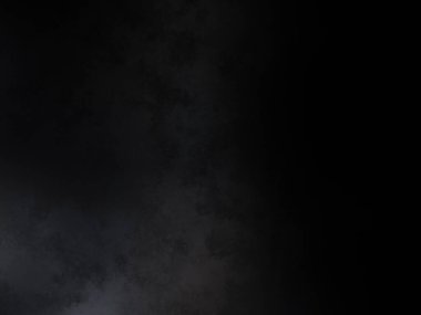 Takım elbiseli ve kravatlı bir adam karanlık bir arka planın önünde duruyor.