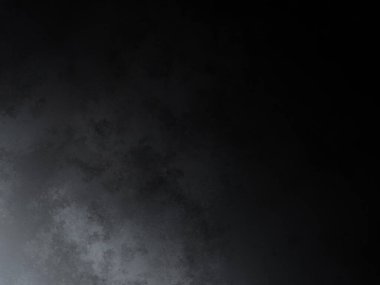 Takım elbiseli ve kravatlı bir adam karanlık bir arka planın önünde duruyor.