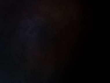 Siyah bir arka planın önünde duran takım elbiseli ve kravatlı bir adam.